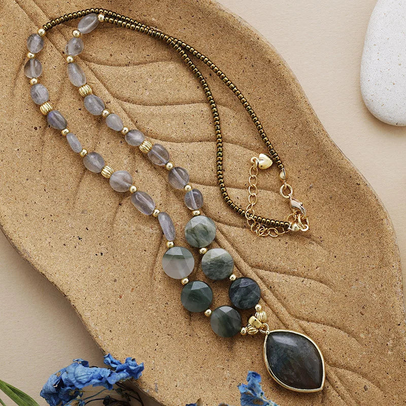 Necklace with beads and a large pendant on a textured surface with flowers.