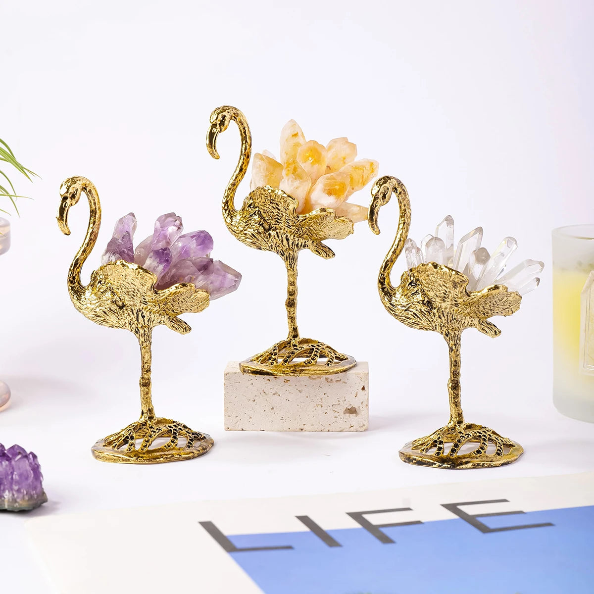 Gold flamingo-shaped candle holders with crystals on a white surface